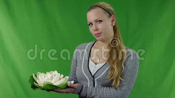 微笑的年轻女孩拿着一朵白色的睡莲面对着视频的预览图