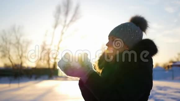 女孩用双手吹雪日落背景视频的预览图