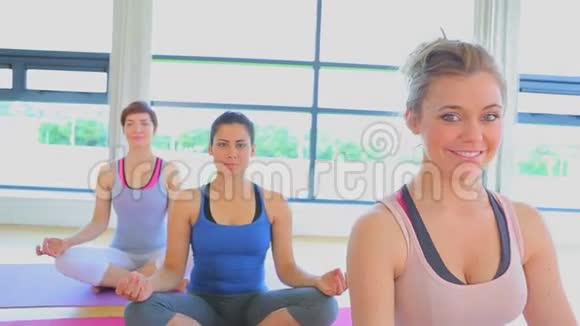 在瑜伽课上微笑的女人坐在瑜伽垫上视频的预览图
