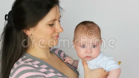 年轻漂亮的留着一头深色长发的母亲在工作室里怀着一个两个月的新生婴儿视频的预览图