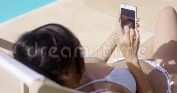 在夏日的阳光下年轻女子在手机上浏览视频的预览图