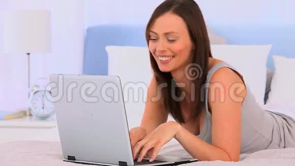 一个拿着笔记本电脑躺在床上的女人视频的预览图