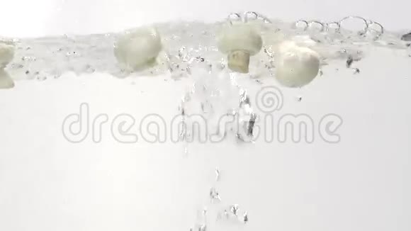 白色蘑菇慢慢地溅入水中视频的预览图