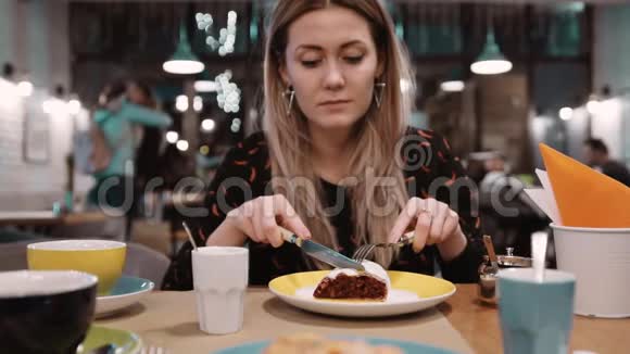 女人用叉子和刀在餐馆吃甜点慢动作视频的预览图
