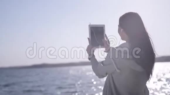 幸福的女人到达海岸用平板电脑拍摄自我画像视频的预览图