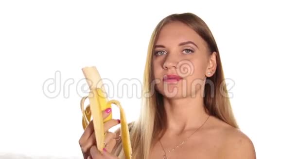 赤裸的年轻女人涂着红色的口红把头发放下来刷着剥着皮吃着一根大香蕉健康食品视频的预览图