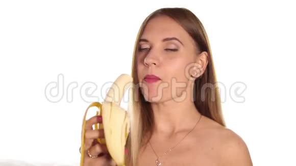 赤裸的年轻女人涂着红色的口红把头发放下来刷着剥着皮吃着一根大香蕉健康食品视频的预览图