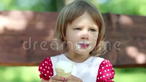 漂亮的女孩坐在长凳上吃冰淇淋视频的预览图