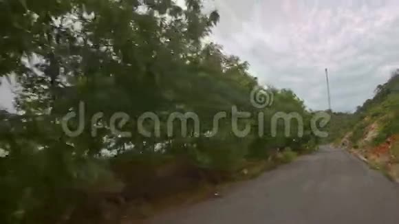 热带树间沥青路的摄像机移动视频的预览图
