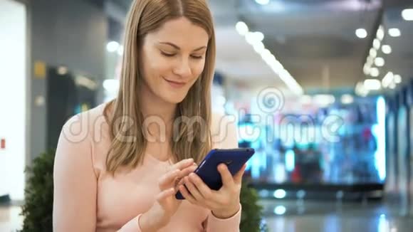 漂亮的女人在商场里用手机说话购物消费主义概念视频的预览图