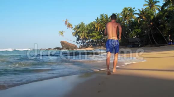 肌肉体操运动员沿着沙海海岸线慢跑视频的预览图