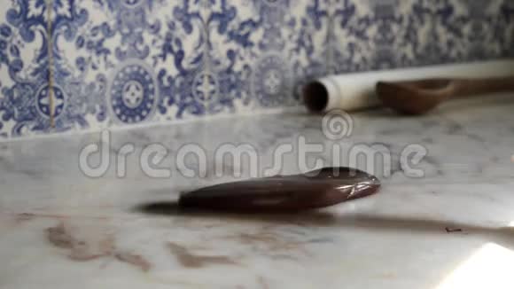 自制烹饪工艺师在大理石台面上用蓝色和白色瓷砖调制光滑的黑巧克力糖果视频的预览图
