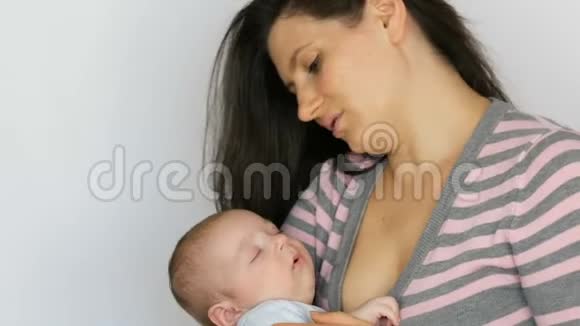 年轻漂亮的留着一头深色长发的母亲在工作室里怀着一个两个月的新生婴儿视频的预览图