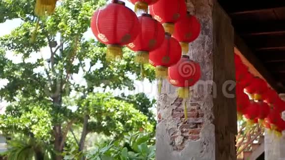破旧建筑上的纸灯笼红纸灯笼挂在阳光明媚的风化混凝土寺庙楼顶视频的预览图