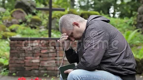 有圣经和念珠在十字架附近的户外教堂祈祷的人视频的预览图