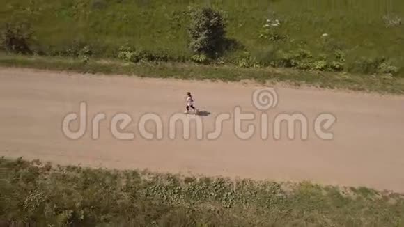 女孩在田野里的路上跑空中观景视频的预览图