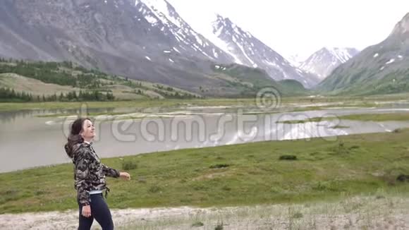 群山背景下的年轻女子奔跑跳舞旅行者视频的预览图