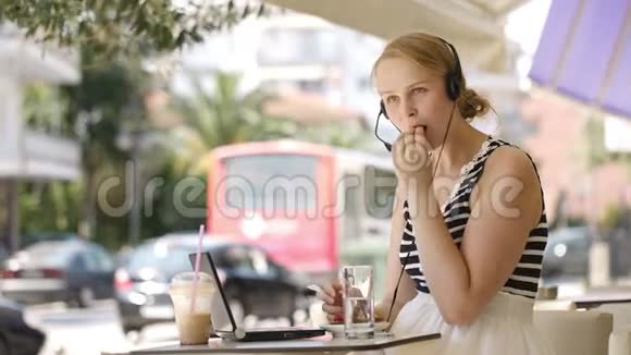 在户外咖啡厅戴耳机大笑的女人视频的预览图