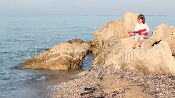 小女孩坐在岩石上弹吉他视频的预览图