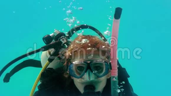 戴着潜水装备的女人在水下看摄像机视频的预览图