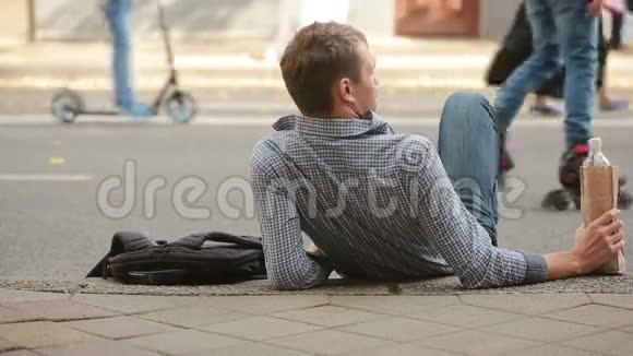 醉汉躺在外面的人行道上从纸袋里喝啤酒的男人视频的预览图