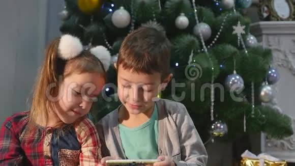 儿童在圣诞树附近玩手机儿童和智能手机视频的预览图