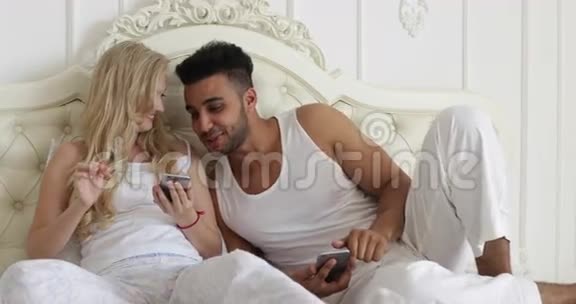情侣卧床使用智能手机混搭男女笑早卧室视频的预览图