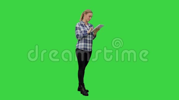 年轻女子站在绿色背景上数字平板电脑在绿色屏幕上Chroma键视频的预览图