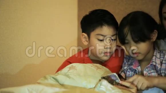 快乐的亚洲家庭在床上玩智能手机时玩得开心在卧室里视频的预览图