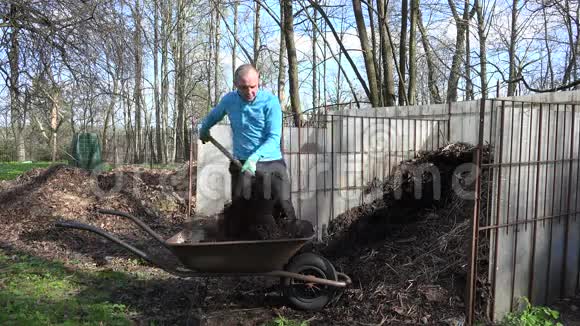 农夫用草叉挖堆肥腐殖质到手推车4K视频的预览图