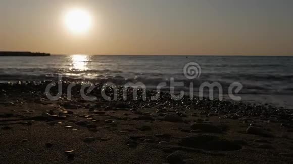 黎明时太阳从海面升起清晨的阳光下海浪和鹅卵石视频的预览图