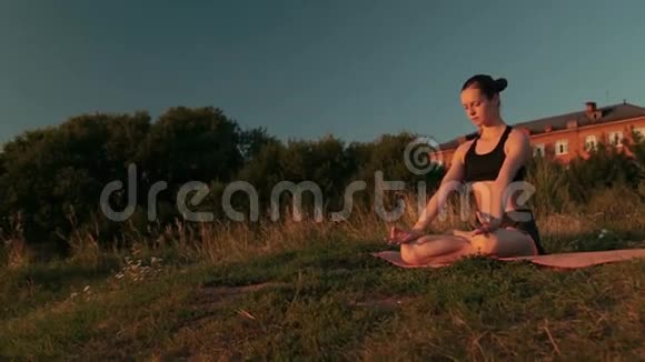 日落时分在公园里莲花位置的运动女人视频的预览图