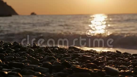 黎明时太阳从海面升起清晨的阳光下海浪和鹅卵石视频的预览图