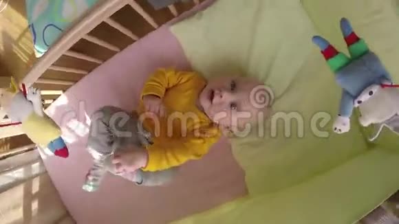 好奇的宝宝看着旋转木马玩具在床上旋转4K视频的预览图