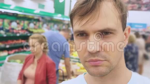 在超市里一位丈夫的脸特写她期待着妻子在商店购物无聊无聊视频的预览图