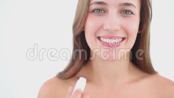 快乐的黑发女人一边用唇膏一边微笑视频的预览图
