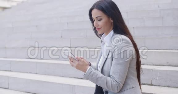 年轻漂亮的工人坐在台阶上打电话视频的预览图
