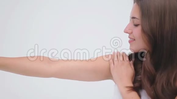 微笑的黑发女人揉着她的手臂视频的预览图