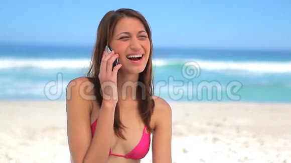 快乐的黑发女人在海滩上打电话视频的预览图