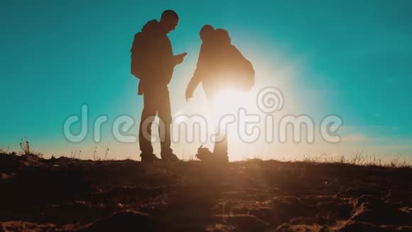 团队合作智能手机导航两名游客徒步旅行者在日落时带着背包去徒步旅行徒步旅行者冒险视频的预览图