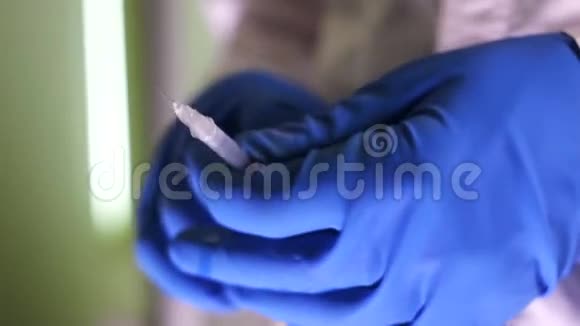 戴蓝手套的医生在注射器里取药视频的预览图