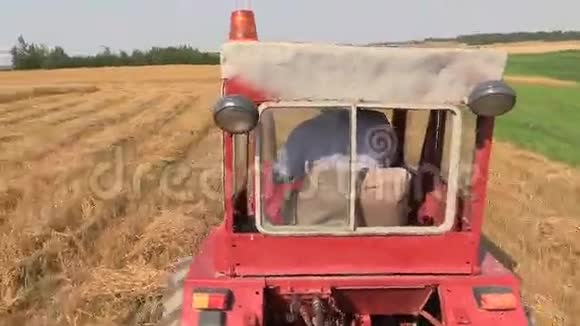农民在农田间开着红色的旧拖拉机视频的预览图