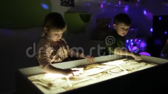 孩子们用手在沙子上画着光视频的预览图