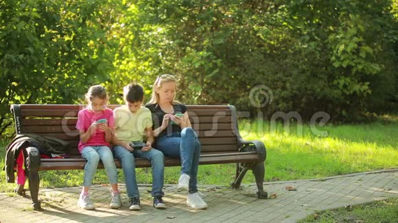母亲带着孩子坐在长凳上使用移动智能手机视频的预览图