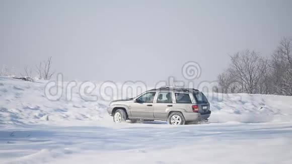 带雪车轮和冬季轮胎的SUV在雪地上行驶视频的预览图