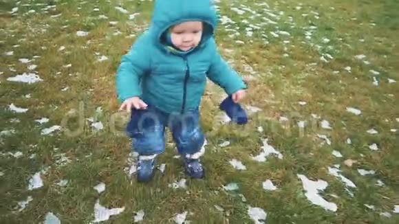 春天孩子沿着人行道跑草地和融化的雪视频的预览图