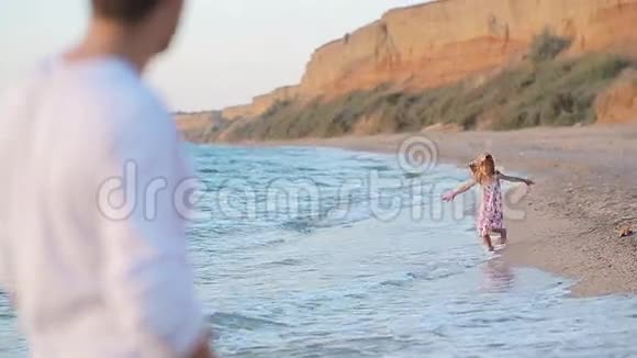 小女孩沿着海滩向父亲跑来视频的预览图