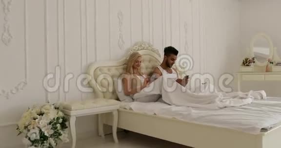 情侣卧床使用智能手机混搭男女笑早卧室视频的预览图