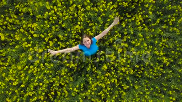 一位年轻女子双臂伸展在黄色的油菜田里视频的预览图