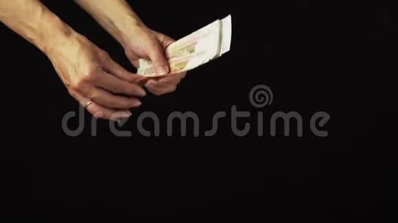 女性手把五千卢布钞票撒在黑色背景慢动作股票录像上视频的预览图